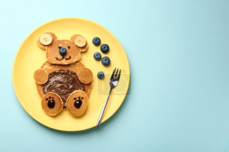 Foto de Servicio creativo para niños. Placa con oso lindo hecha de panqueques, arándanos, plátanos y pasta de chocolate en la mesa azul claro, vista superior. Espacio para texto - Imagen libre de derechos