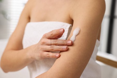 Woman applying self-tanning product onto arm indoors, closeup