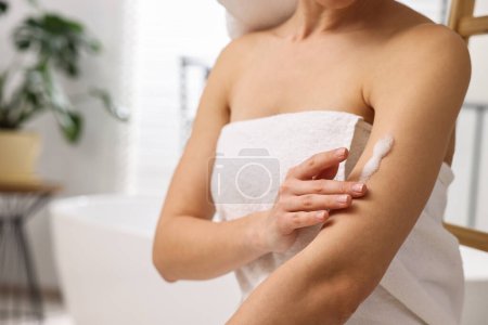 Foto de Mujer aplicando producto auto-bronceado en el brazo en el baño, primer plano. Espacio para texto - Imagen libre de derechos