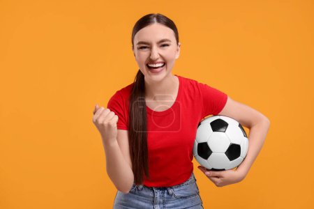 Photo for Happy soccer fan with ball celebrating on orange background - Royalty Free Image