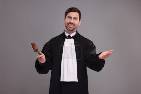 Happy judge with gavel on grey background