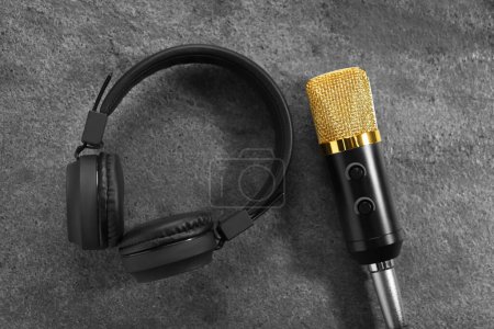 Microphone and headphones on grey textured background, flat lay. Sound recording and reinforcement
