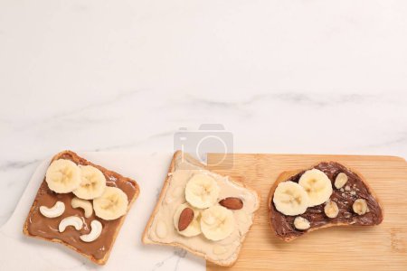 Photo for Toasts with different nut butters, banana slices and nuts on white marble table, flat lay. Space for text - Royalty Free Image