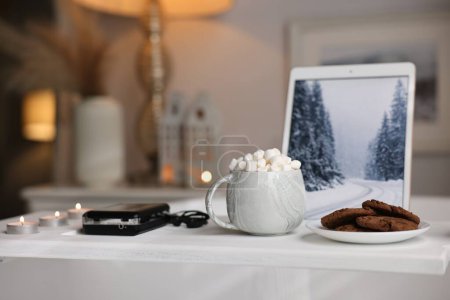 Téléchargez les photos : Plateau en bois blanc avec tablette, lecteur cassette, biscuits et bougies allumées sur la baignoire dans la salle de bain - en image libre de droit
