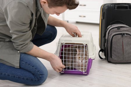 Téléchargez les photos : Voyage avec animal de compagnie. Homme fermeture transporteur avec chat à l'intérieur - en image libre de droit