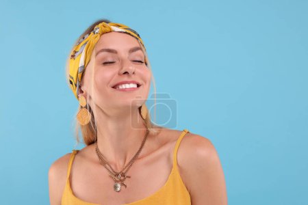 Portrait of happy hippie woman on light blue background. Space for text