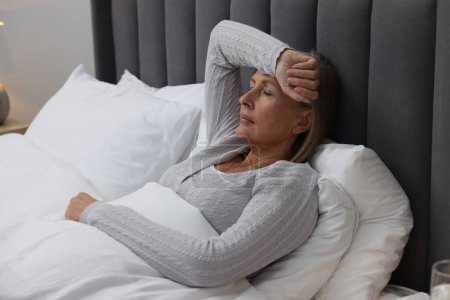 Photo for Menopause. Woman suffering from headache in bed indoors - Royalty Free Image