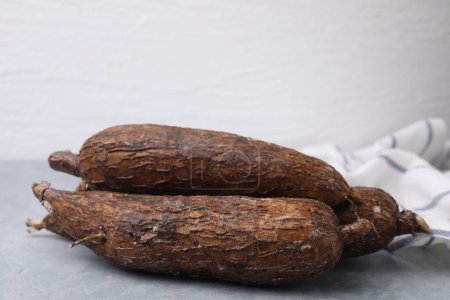 Téléchargez les photos : Racines de manioc entières fraîches sur table grise, gros plan - en image libre de droit