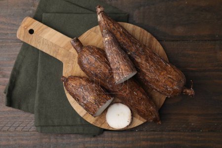 Téléchargez les photos : Racines de manioc entières et coupées sur table en bois, vue de dessus - en image libre de droit