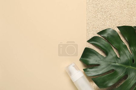 Photo for Bath accessory. Bottle of cosmetic product and palm leaf on beige background, top view. Space for text - Royalty Free Image