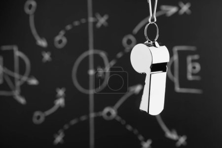 Referee whistle against chalkboard with game scheme, closeup. Space for text