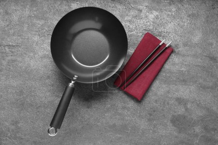 Photo for Empty iron wok and chopsticks on grey table, flat lay - Royalty Free Image