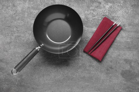 Photo for Empty iron wok and chopsticks on grey table, flat lay - Royalty Free Image