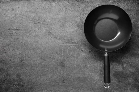 Photo for Empty iron wok on grey textured table, top view. Space for text - Royalty Free Image