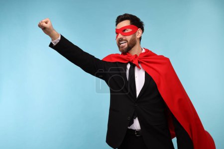 Foto de Hombre de negocios con capa de superhéroe rojo y máscara sobre fondo azul claro - Imagen libre de derechos