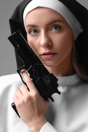 Photo for Woman in nun habit holding handgun on grey background, closeup - Royalty Free Image