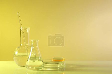 Photo for Laboratory analysis. Different glassware on table against yellow background, space for text - Royalty Free Image