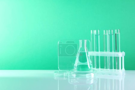 Photo for Laboratory analysis. Different glassware on table against green background, space for text - Royalty Free Image