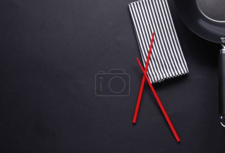 Photo for Empty iron wok and chopsticks on black table, flat lay. Space for text - Royalty Free Image