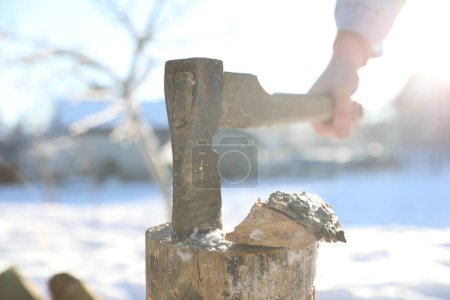 Mann holt an sonnigem Tag Axt aus Holzscheit, Nahaufnahme