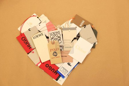 Foto de Leiden, Países Bajos - 6 de diciembre de 2023: Corazón de diferentes etiquetas de ropa en la hoja de papel kraft, vista superior - Imagen libre de derechos
