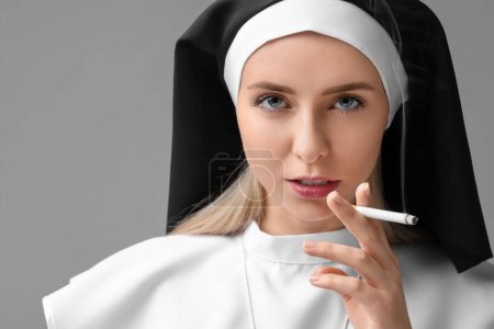 Foto de Mujer con hábito de monja fumando cigarrillo sobre fondo gris. Espacio para texto - Imagen libre de derechos