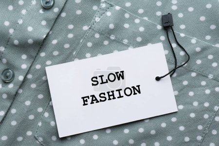 Bewusster Konsum. Tag mit Worten Slow Fashion auf Hemd, Ansicht von oben