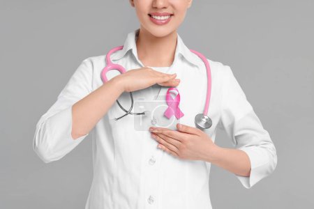 Mamólogo con cinta rosa sobre fondo gris, primer plano. Concientización sobre el cáncer de mama