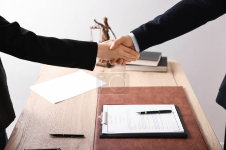 Notar schüttelt Klientin am Holztisch im Büro die Hand, Nahaufnahme