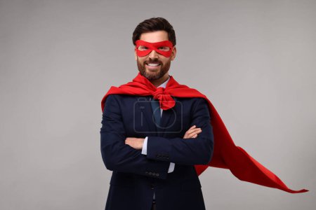 Foto de Feliz hombre de negocios con capa de superhéroe rojo y máscara sobre fondo beige - Imagen libre de derechos