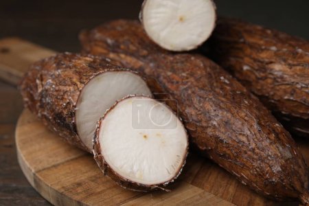 Téléchargez les photos : Racines de manioc entières et coupées sur table en bois, gros plan - en image libre de droit