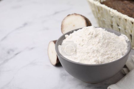 Téléchargez les photos : Bol avec farine de manioc et racines sur table en marbre blanc. Espace pour le texte - en image libre de droit