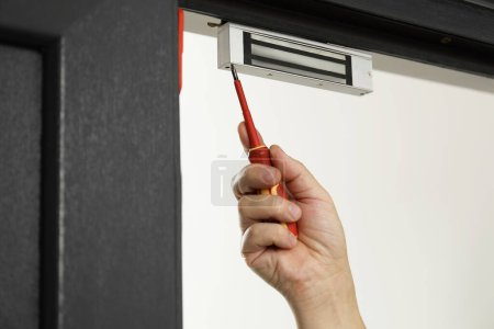 Photo for Man with screwdriver installing electromagnetic door lock indoors, closeup. Home security - Royalty Free Image