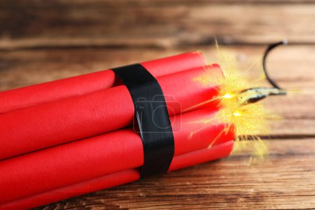 Photo for Dynamite bomb with lit fuse on wooden table, closeup - Royalty Free Image