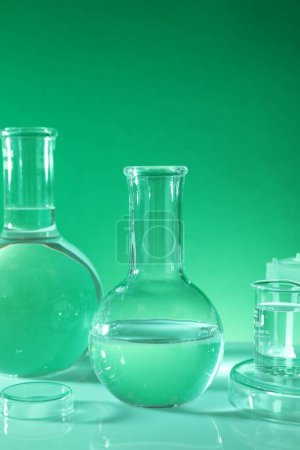 Photo for Laboratory analysis. Different glassware on table against green background - Royalty Free Image