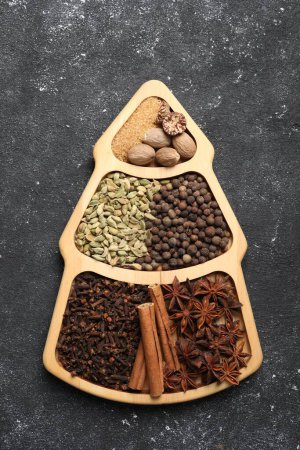 Different spices and nuts on dark gray textured table, top view