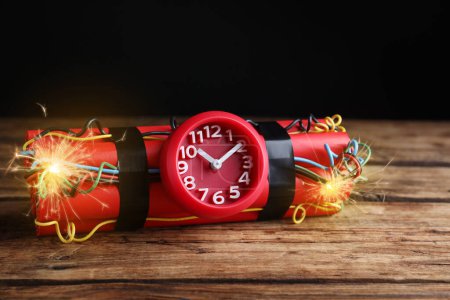Photo for Dynamite time bomb with burning wires on wooden table - Royalty Free Image