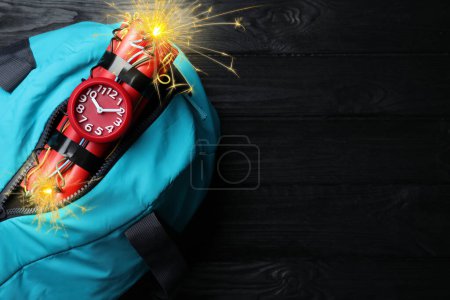 Photo for Dynamite time bomb with burning wires in bag on black wooden table, top view. Space for text - Royalty Free Image