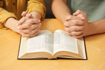 Photo for Family couple praying over Bible together at table indoors, closeup - Royalty Free Image