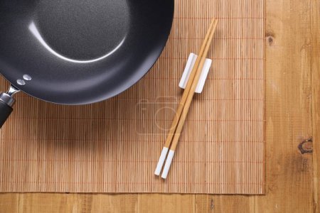 Photo for Empty iron wok and chopsticks on wooden table, top view - Royalty Free Image