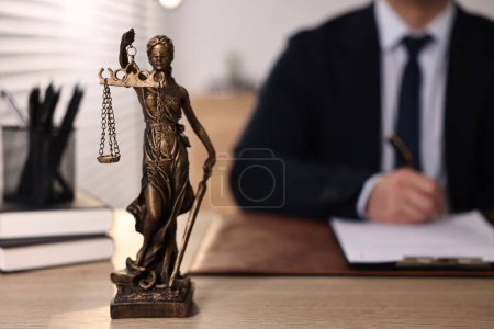 Photo for Notary writing notes at wooden table in office, focus on statue of Lady Justice - Royalty Free Image