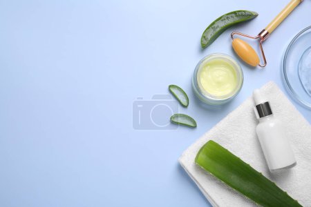 Flat lay composition with cosmetic products and cut aloe leaves on light blue background. Space for text