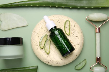 Flat lay composition with cosmetic products and cut aloe leaves on pale green background