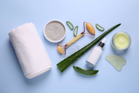 Flat lay composition with cosmetic products and cut aloe leaves on light blue background