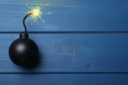 Photo for Old fashioned black bomb with lit fuse on blue wooden table, top view. Space for text - Royalty Free Image