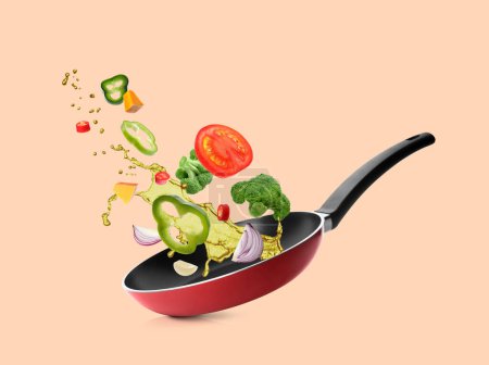 Different vegetables, oil, frying pan in air on pale coral background