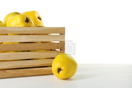 Crate with delicious fresh ripe quinces on light wooden table against white background, space for text
