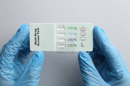 Photo for Doctor holding multi-drug screen test on light grey background, top view - Royalty Free Image