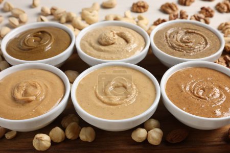 Photo for Many tasty nut butters in bowls and nuts on table, closeup - Royalty Free Image