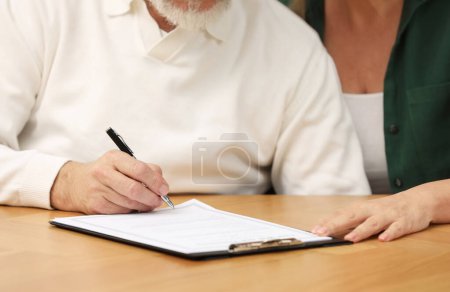 Foto de Pareja mayor firmando Última Voluntad y Testamento en mesa de madera, primer plano - Imagen libre de derechos